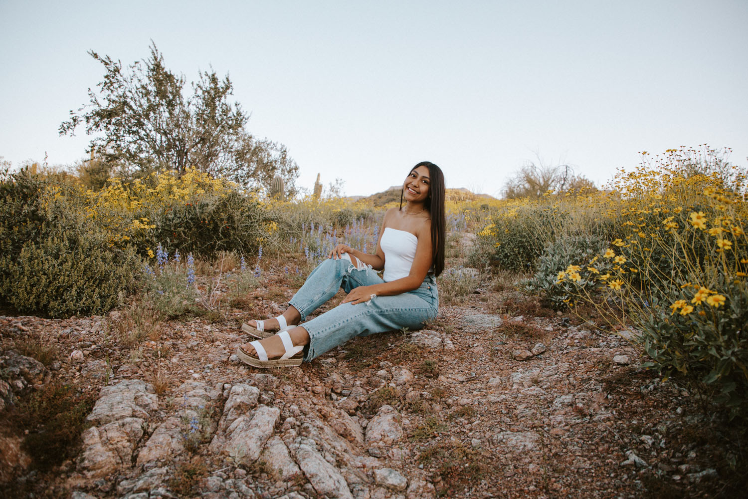 Ava sitting, smiling for the camera in a desert landscape