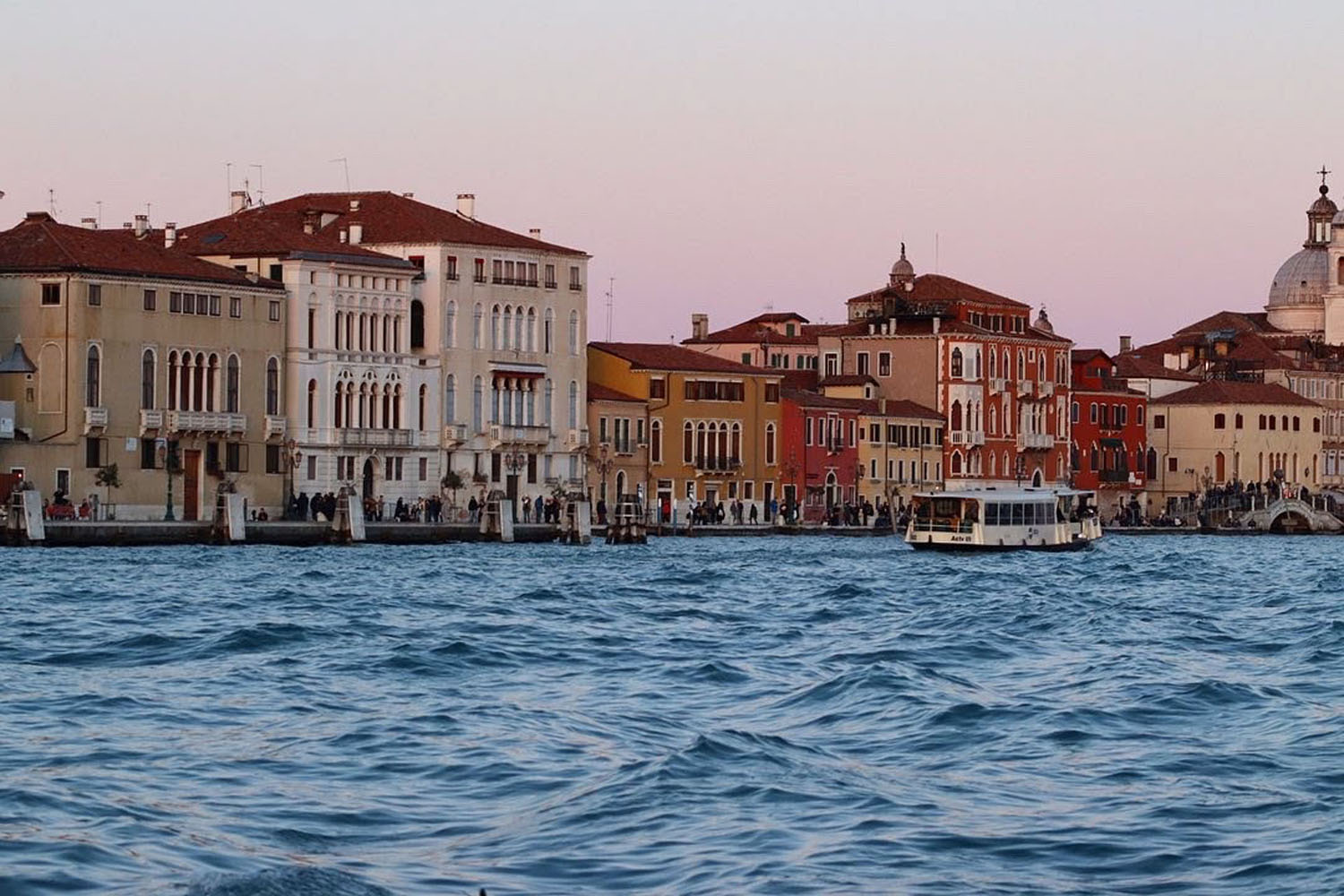 Boat on the water in front of a row of homes Boat on the water in front of a row of homes